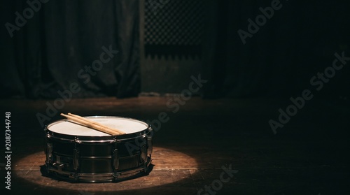 Obraz na płótnie Snare drum and drumsticks on a wooden stage under spotlight