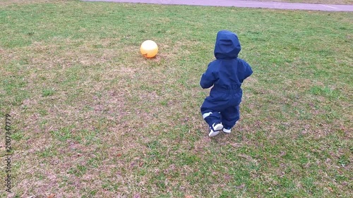 Toddler walking on grass towards a ball