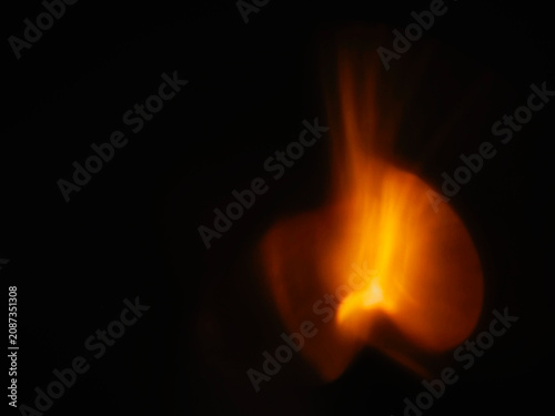Soft, glowing orange light against dark background. Abstract bokeh effect with warm tones. Suitable for atmospheric or mystical compositions. No animals or plants visible. Light leak for design.