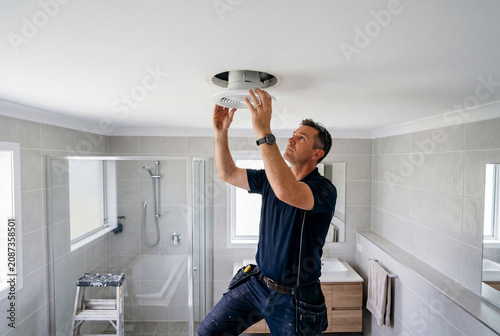Electrician Installing Exhaust Fan in Bathroom Ceiling
