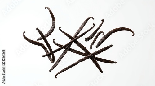 Premium organic dried vanilla beans scattered on white background for gourmet baking and aromatic flavoring