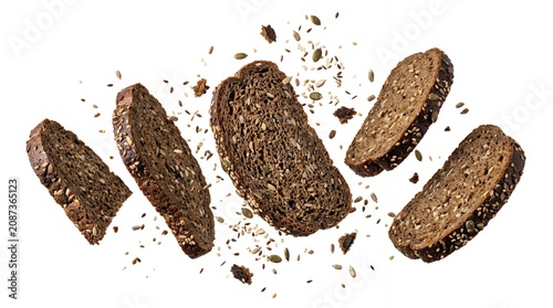 Slices of dark multigrain bread with seeds falling and flying in motion isolated on white background. Healthy food.