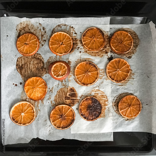 Dried orange slices arranged on parchment paper on a baking tray.
