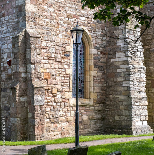 An ornate vintage street lamp stands within a churchyard, its decorative ironwork adding character and charm to this peaceful historic setting.