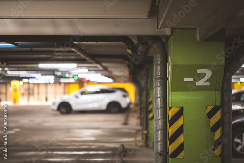 Bild auf Leinwand Underground parking garage with a white car and green painted pillars