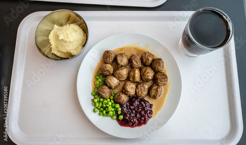 Traditional meatball meal with mashed potatoes peas and berry sauce.