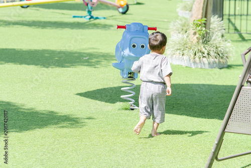 Obraz na plátně Toddler playing on a blue spring rider at a sunny outdoor playground in a bright