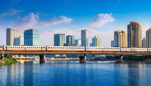 train traveling along river with city skyline background