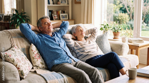 Relaxed mature couple resting on sofa with eyes closed at home