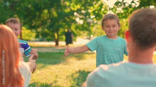 Little boys girls hug parents in park. Happy people. Children run outdoors, hugging parents. Family weekend. Happy family. Parents fun, dad mom, kids son daughter having picnic on lawn. Kids smiling