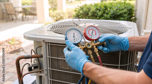 HVAC technician checking air conditioning unit with manifold gauge. Professional service and maintenance of outdoor AC condenser