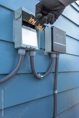 Canvas Print Side view of electrician hand removing a pullout switch disconnect from an outdo