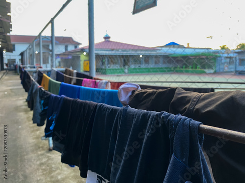 Obraz na plátně Clothes hanging on a drying rack inside a prison facility