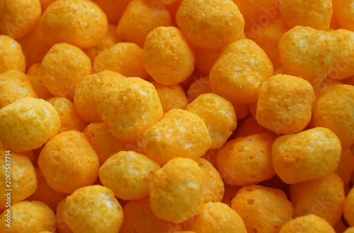 Bright orange cheese balls showing crunchy, puffed texture and uniform spherical shape