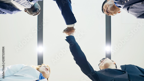 Fotografie Group of multinational businesspeople high-fiving, viewed from below
