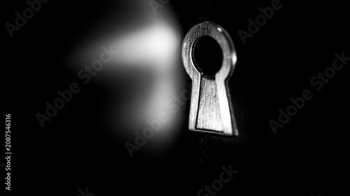 Close up of a keyhole in dramatic lighting on a dark background