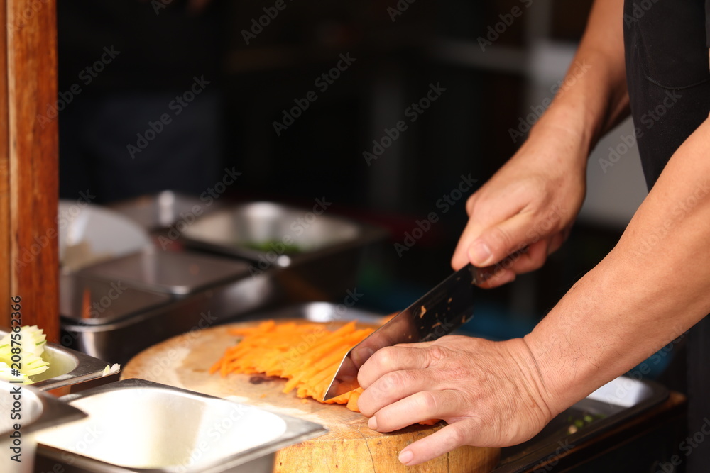 Fototapeta premium Chef Hands Slicing Fresh Carrots into Julienne Strips on Wooden Board