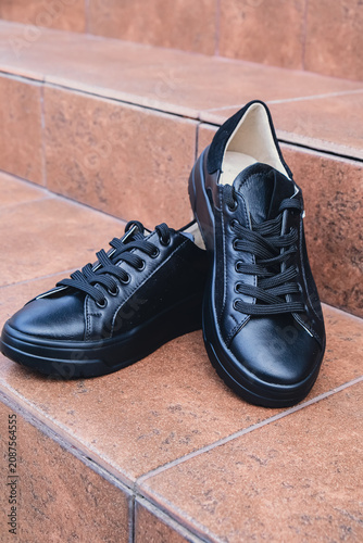 Elegant black leather womens shoes blank product for branding displayed. New casual female sneakers no-brand footwear e-commerce. No logo product unbranded fashion