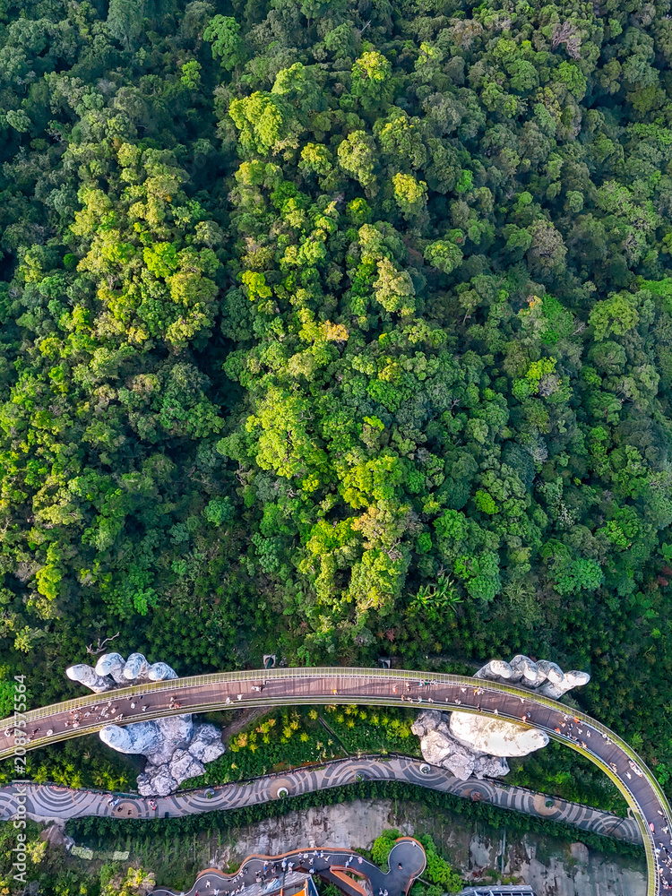 Obraz premium Aerial top view of the bridge hands on top of a mountain surrounded by forest