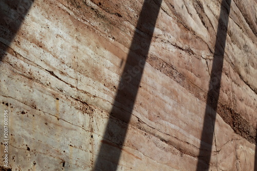 Obraz na plátně Close-up of layered rammed earth wall with distinct strata and shadow patterns