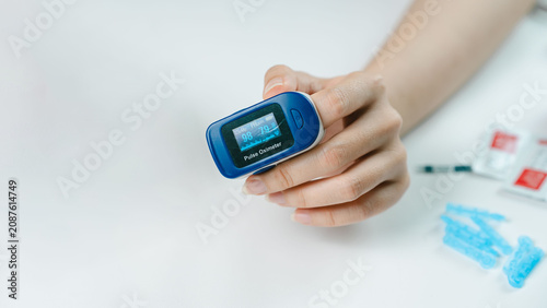 Фотография Close-up of an adult using a fingertip pulse oximeter to measure blood oxygen saturation and pulse rate at home