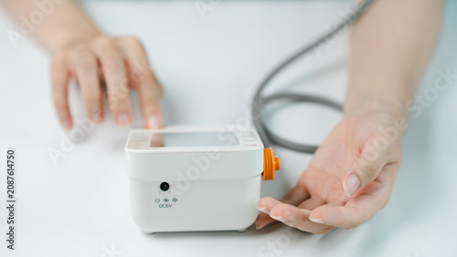 Photos Close-up of an adult operating a digital blood pressure monitor during a home health check