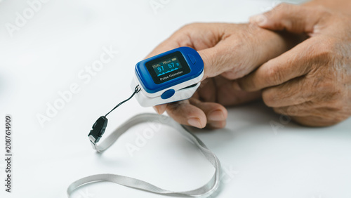 Obraz na plátně Close-up of a senior adult using a fingertip pulse oximeter to measure blood oxygen saturation and pulse rate at home