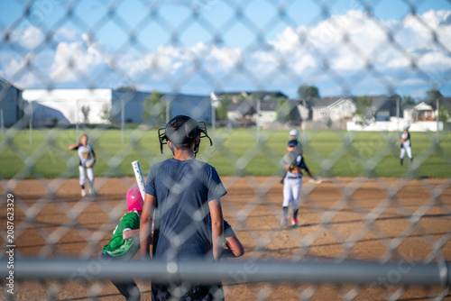 Obraz na plátně Batter prepares to hit during a softball game with umpire observing on the field