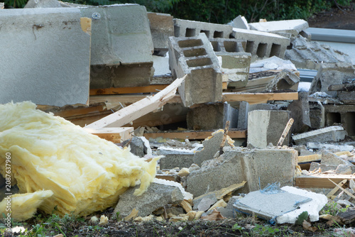 фотографія A large, jumbled pile of mixed construction and demolition waste, featuring broken concrete blocks, yellow fiberglass insulation, and splintered wood debris