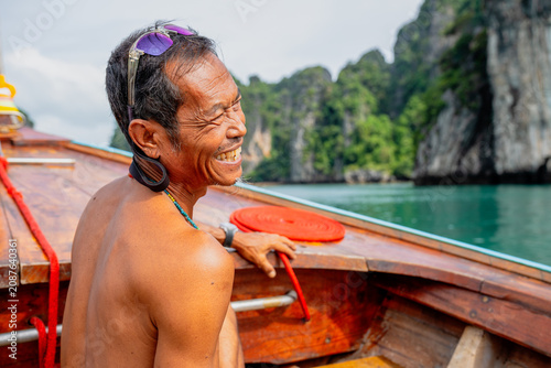 Thai boatman smiling enjoying longtail boat ride