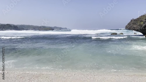 Scenic Tropical Beach with Rolling Ocean Waves and Rocky Cliff