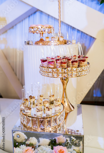 Cuadro en lienzo Mesa de postres elegante con copas de postre, bandejas doradas y decoración flor