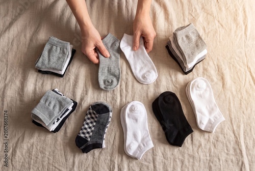 Person Organizing Folded Socks on a Linen Bed Sheet