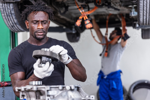 Professional EV technician repairing an electric drive unit and powertrain components in a modern electric vehicle service center. Concept of electric vehicle maintenance