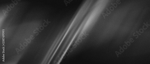 Abstract dark background with diagonal soft white light rays and subtle grain texture for minimalist design projects requiring a clean