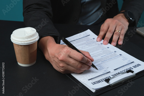 Obraz na plátně Focused businessman using black pen to sign confidential non disclosure agreemen