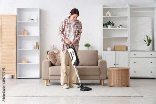 Young woman vacuuming carpe...