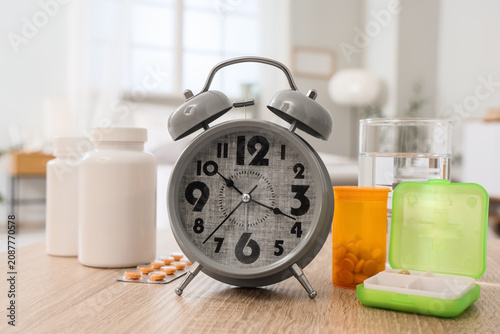 Canvastavla Alarm clock with pills and glass of water on table in bedroom, closeup