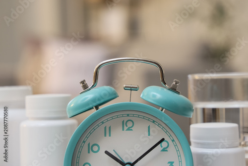 Photos Alarm clock with pills on table in room