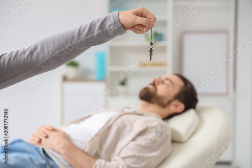 Obraz na plátně Female psychologists hand with pendulum hypnotizing man on couch in office, clos
