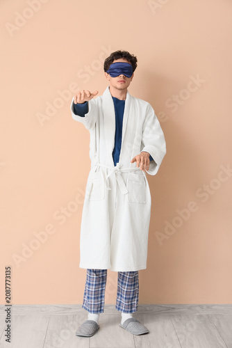 Принти на полотні Young male sleepwalker in bathrobe with sleeping mask on beige background