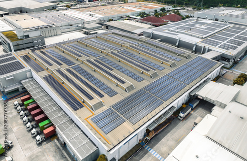 Solar-powered warehouse facility with freight trucks at loading docks. Eco-friendly logistics and efficient cargo transportation. Solar panels and sustainable energy concept in distribution center.