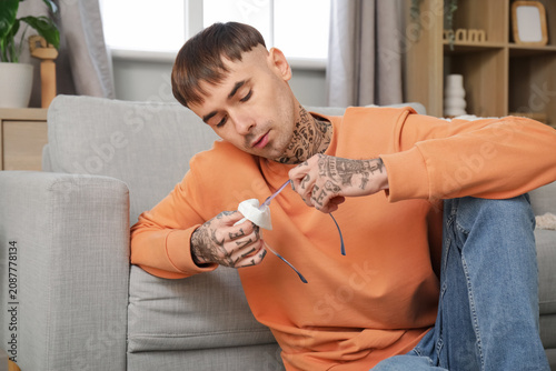Young tattooed man wiping e...