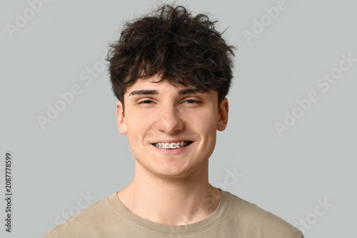 фотографія Smiling young man with dental braces on light background
