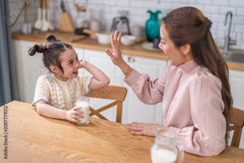 Happy asian mother giving glass of milk to little daughter at breakfast, Smiling female parent and cute child enjoying healthy nutrition for growth and calcium, Family lifestyle and health concept