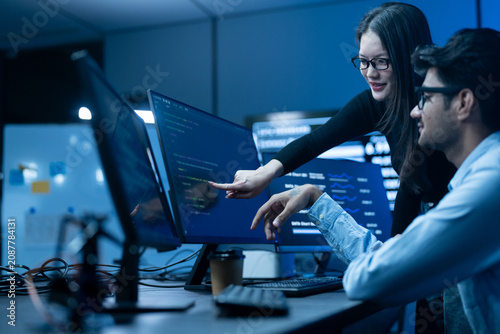 Cuadro en lienzo Asian happy woman and man programmer team coding software at computer in dark te