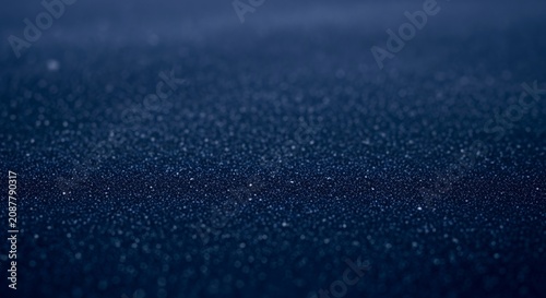 Raindrops falling on a dark, wet surface creating a textured and reflective pattern, evoking a sense of calm and natural beauty.