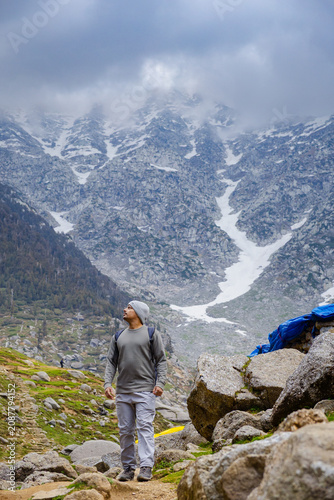 Hiker standing at Kareri Lake in Dharamshala Himachal Pradesh with snowy mountain peaks in background