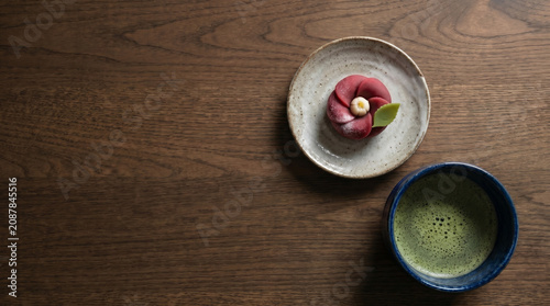 Traditional Japanese winter wagashi camellia nerikiri with matcha on dark wood table