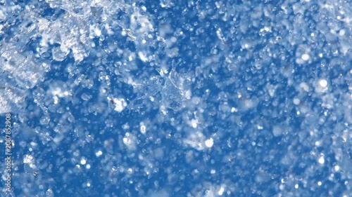 Close-up of sparkling fountain water splashes against clear blue sky. Refreshing droplets create dynamic abstract background representing freshness, summer, energy and motion